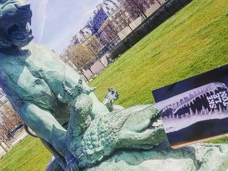 Photo du livre devant une statue du jardin des Tuileries à Paris qui montre un lion terrassant un crocodile. La machoire de crocodile sur la couverture du livre est située dans le prolongement de la statue de crocodile.