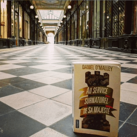 Photo du livre sur lequel figure une tour d'échecs posé sur le damier au sol du passage Véro-Dodat à Paris