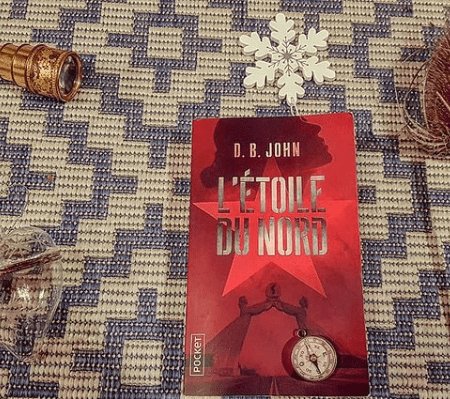 Photo du livre entouré de plusieurs objets : une fleur séchée, une boussole indiquant le nord, une étoile blanche, une petite longue vue et une décoration en verre